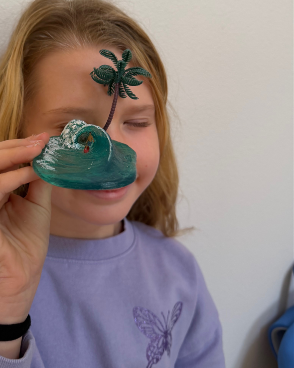 Child viewing lens on handcrafted surf barrel sculpture